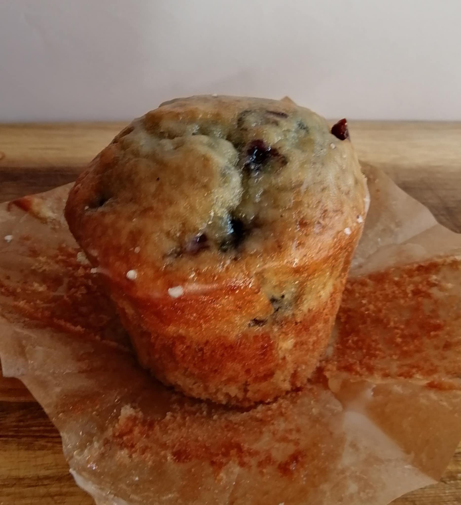 Blueberry & Lemon muffin with a lemon glaze on a wooden surface with a white background